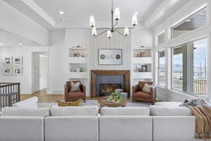 Living room featuring light hardwood / wood-style flooring, a high end fireplace, built in features, and a raised ceiling