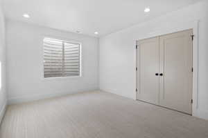 Unfurnished bedroom with light colored carpet and a closet