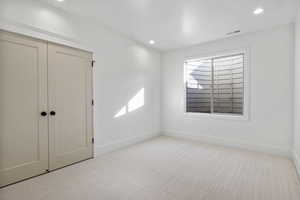 Unfurnished bedroom with light colored carpet and a closet