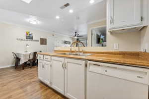 Kitchen with ceiling fan, sink, light hardwood / wood-style flooring, white cabinetry, and dishwasher