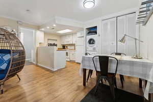 Dining room with stacked washer / dryer, light hardwood / wood-style floors, and crown molding