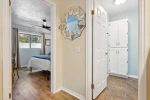 Corridor with light wood-type flooring and a textured ceiling