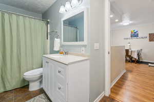 Bathroom featuring vanity, curtained shower, a textured ceiling, hardwood / wood-style flooring, and toilet