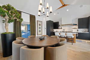 Dining space with beamed ceiling, light wood-type flooring, a chandelier, and high vaulted ceiling