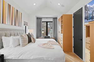 Bedroom with light hardwood / wood-style floors and lofted ceiling