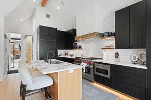 Kitchen featuring tasteful backsplash, an island with sink, light hardwood / wood-style floors, and a kitchen bar