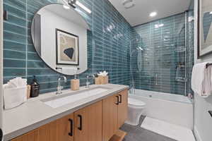 Full bathroom featuring backsplash, toilet, tile walls, and enclosed tub / shower combo