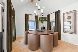 Dining room featuring a notable chandelier, vaulted ceiling with beams, and light hardwood / wood-style floors