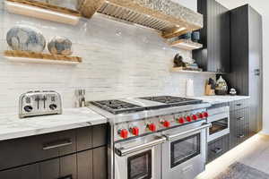 Kitchen with range with two ovens, light stone countertops, decorative backsplash, and hardwood / wood-style flooring