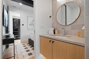 Bathroom with hardwood / wood-style flooring, vanity, and decorative backsplash