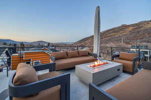 Patio terrace at dusk with a mountain view and an outdoor living space with a fire pit