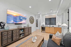 Living room featuring light wood-type flooring, beverage cooler, and sink