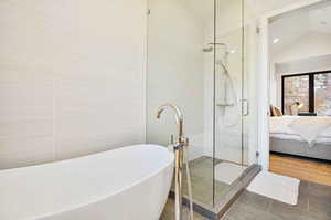 Bathroom with separate shower and tub, tile patterned flooring, and vaulted ceiling