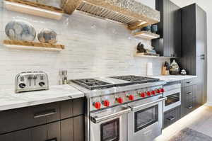 Kitchen featuring light stone countertops, backsplash, hardwood / wood-style floors, and double oven range