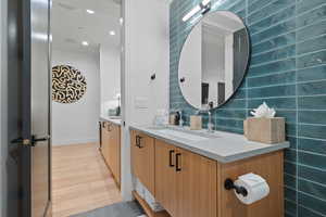 Bathroom with vanity, wood-type flooring, and tasteful backsplash