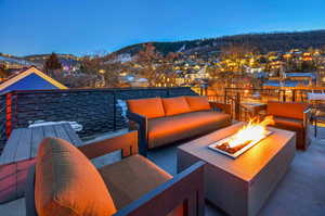 Patio terrace at dusk with a mountain view and an outdoor living space with a fire pit