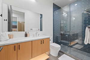 Bathroom with tile patterned floors, vanity, toilet, and an enclosed shower