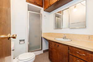 Bathroom with a shower with door, vanity, and toilet