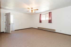 Carpeted empty room featuring ceiling fan, a textured ceiling, and a baseboard heating unit