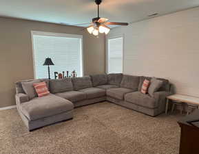 Living area features carpeted flooring, a custom shiplap wall and large windows with plenty of natural light