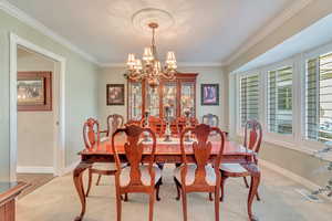 Dining area featuring an inviting chandelier, crown molding, and a healthy amount of sunlight