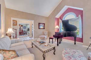 Carpeted living room with lofted ceiling and a healthy amount of sunlight