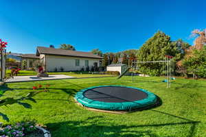 View of property's community with a playground, a yard, a trampoline, and a patio area