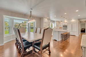 Dining room with light hardwood / wood-style flooring, a textured ceiling, and an inviting chandelier