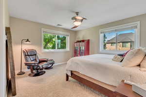 Bedroom with multiple windows, ceiling fan, and carpet floors