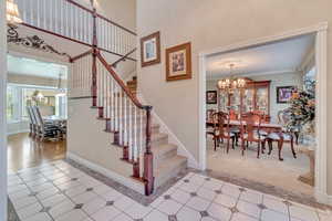 Stairs with a notable chandelier, carpet flooring, and tile flooring