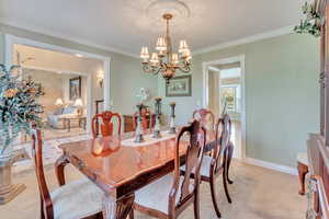 Carpeted dining room with crown molding and a chandelier