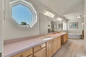 Master Bathroom with vanity, a tub, and vaulted ceiling