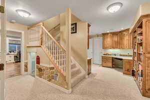 Interior space with a textured ceiling, built in desk, and carpet flooring