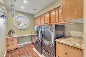 Clothes washing area with dark hardwood / wood-style floors, washer and dryer, and cabinets