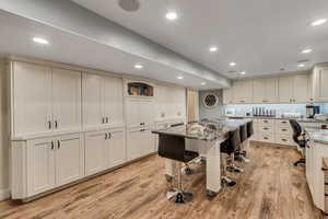 Craft Room w/ light stone counters, white cabinets, an island, and light LVP flooring