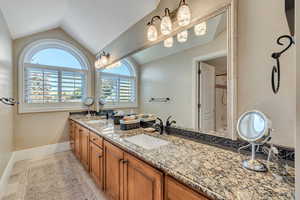 Guest Bathroom featuring walk in shower, vanity, lofted ceiling, and tile patterned floors