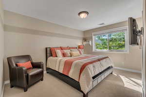 Bedroom featuring light carpet and a wall mounted air conditioner