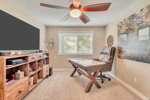 Carpeted office featuring ceiling fan