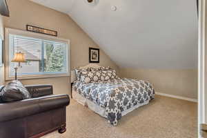 Carpeted bedroom with vaulted ceiling and ceiling fan