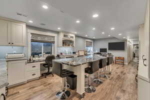 Craft Room with white cabinets, LVP flooring, built in desk, dark stone countertops