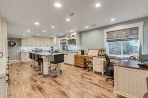 Craft Room with light LVP flooring, white cabinetry, and an island