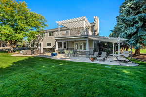 Rear view of property featuring a pergola, a yard, a balcony, and a patio area