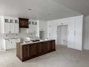 Kitchen featuring white cabinets, a kitchen island, and dark brown cabinetry