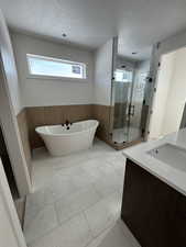 Bathroom with vanity, independent shower and bath, and a textured ceiling