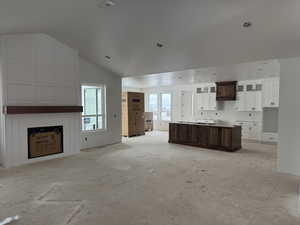 Kitchen featuring a center island, dark brown cabinetry, white cabinetry, and vaulted ceiling