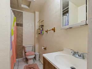 Bathroom featuring vanity, a textured ceiling, walk in shower, toilet, and tile patterned floors