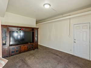 Unfurnished living room featuring dark colored carpet