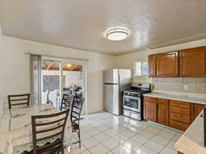 Kitchen featuring appliances with stainless steel finishes, light tile patterned floors, and tasteful backsplash