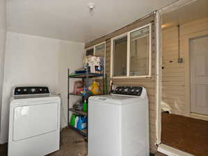 Clothes washing area featuring washer and clothes dryer and wooden walls