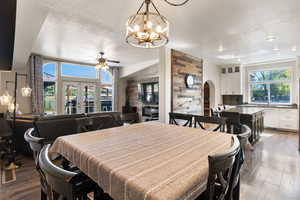 Dining room featuring hardwood / wood-style flooring, ceiling fan with notable chandelier, and a textured ceiling